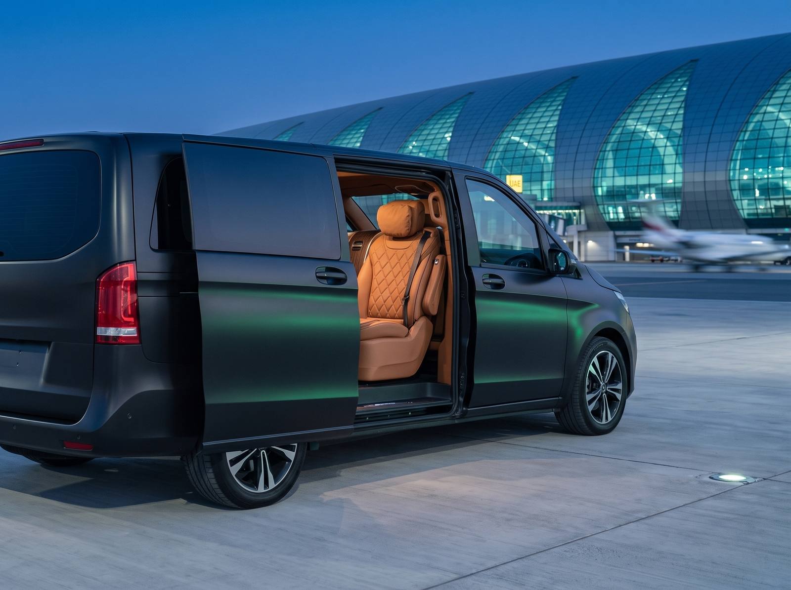 An executive van with its sliding door open at a UAE airport terminal